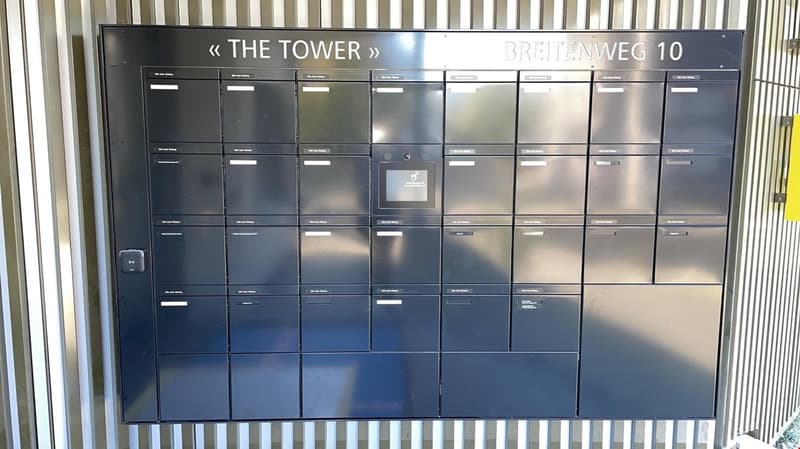 Storage lockers on the wall with sign reading 'THE TOWER' and 'BREITENWEG 10'.