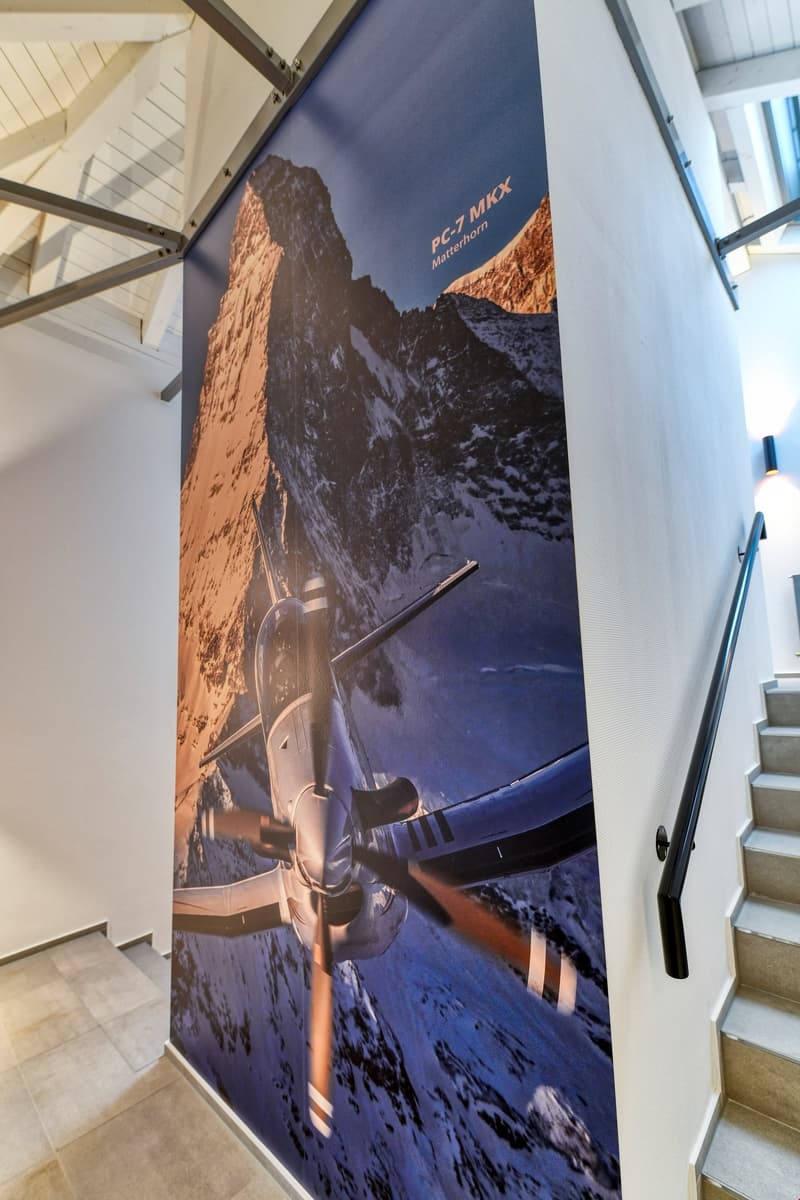 wall with big plane poster, tile floor, wall-mounted stair rail, light mounted to wall