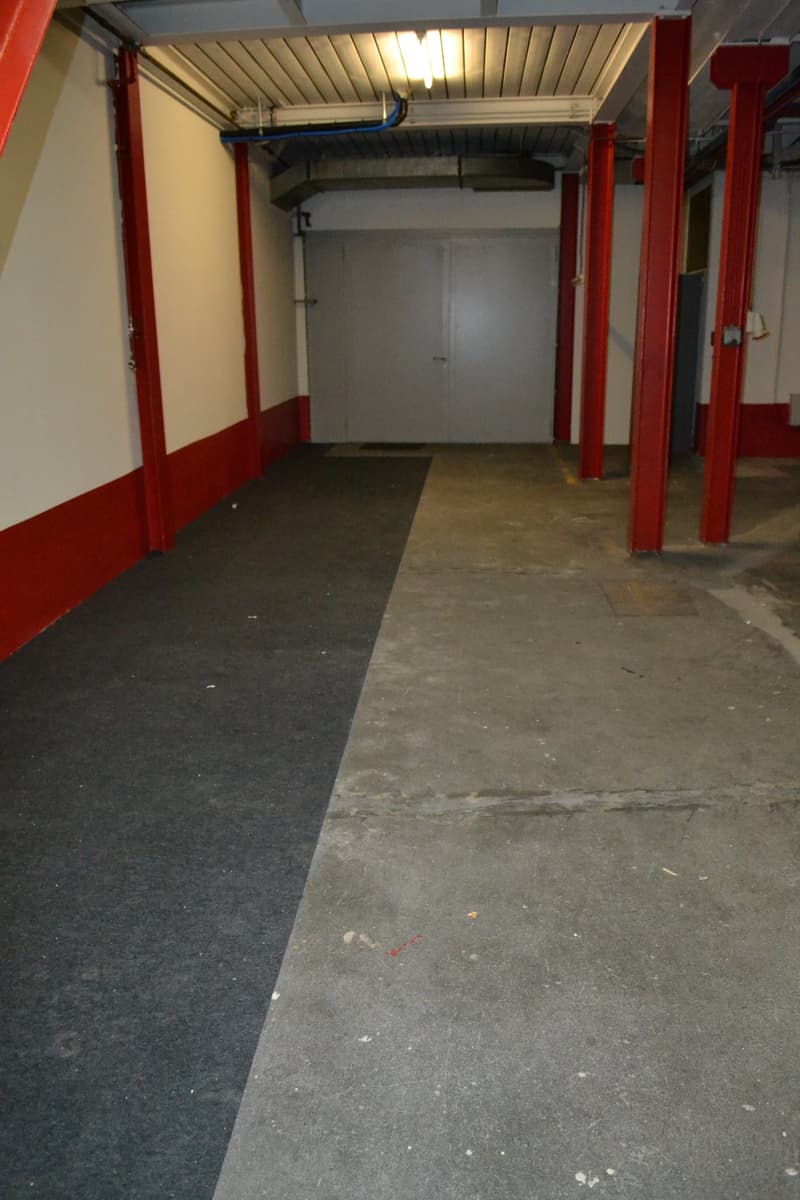 Empty garage with concrete floor, red pillars, white walls, and a white door.