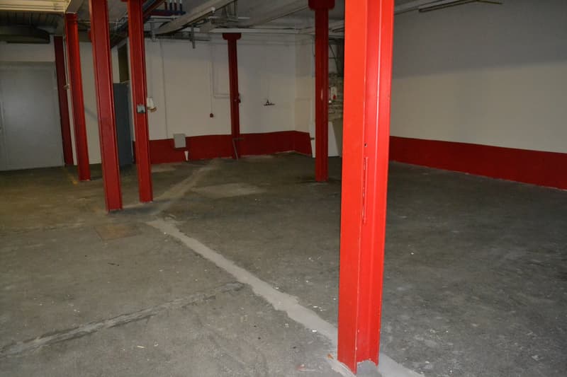 Empty parking lot with red pillars, concrete floor, white walls, ceiling with lights