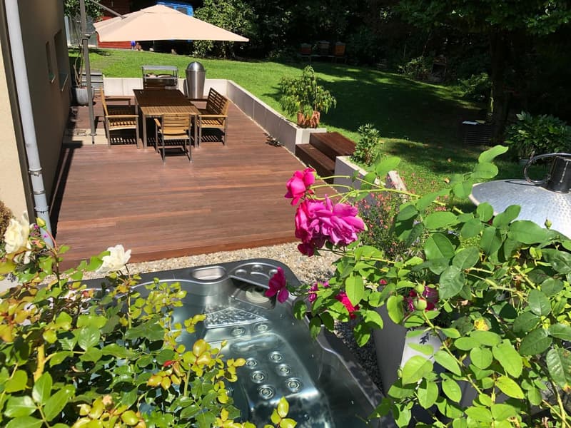 wooden deck, outdoor dining table, chairs, umbrella, hot tub, plants, flowers