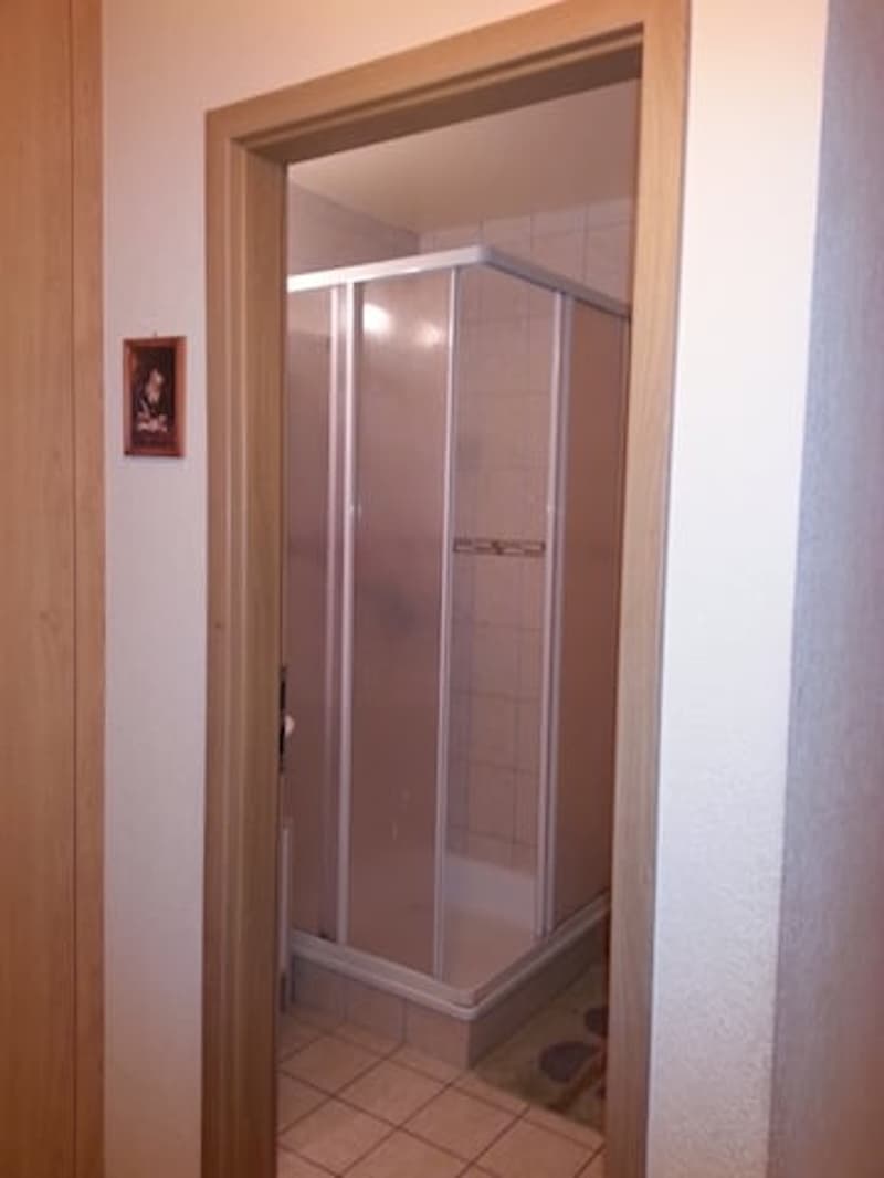 Bathroom with shower, tiled floor, wooden door, picture frame on the wall