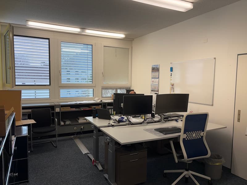 office room with desks, monitors, chairs, cabinets, whiteboard, trash can, open door