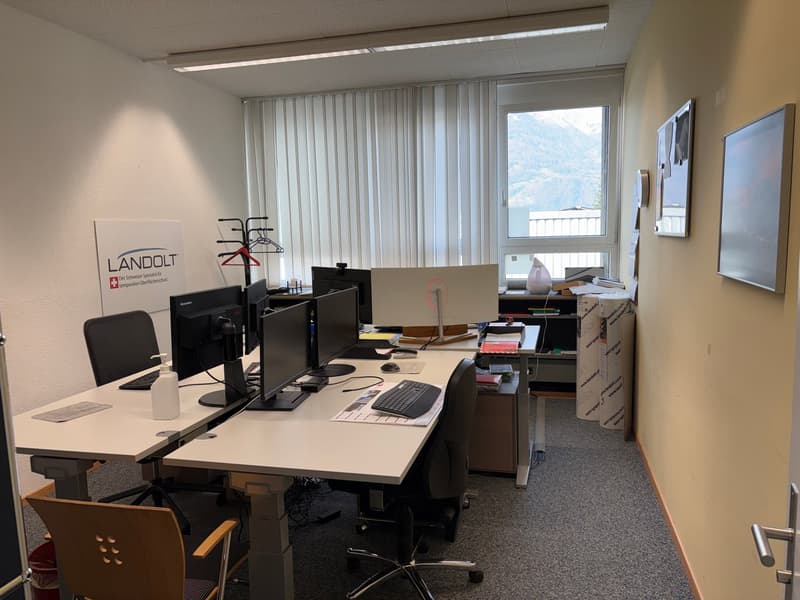 Office space with desks, monitors, chairs, fire extinguisher, shelves, blinds, windows with view, light fixtures