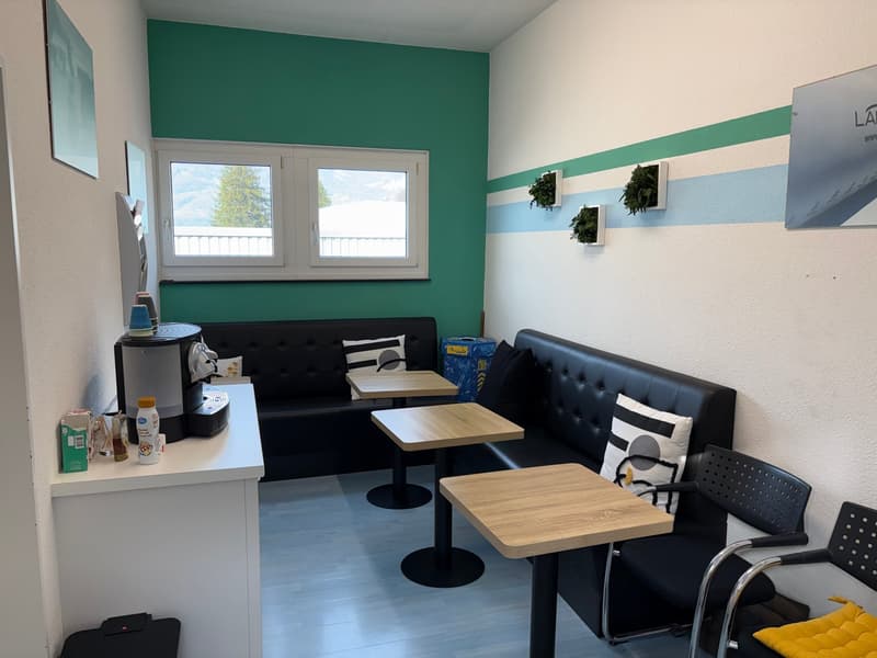 small meeting room, green wall, black couch, two tables, window