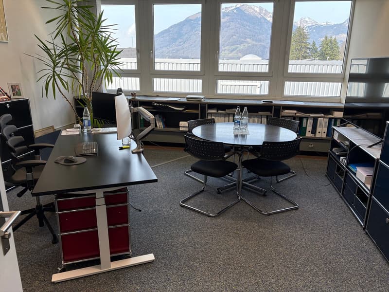 black desks, black chairs, office equipment, large windows with mountain view