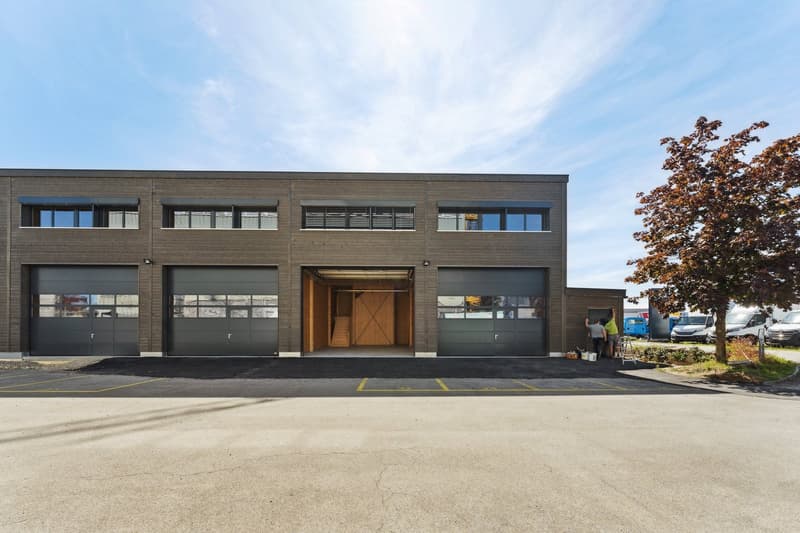 modern building with large double doors, large windows, grey garage doors