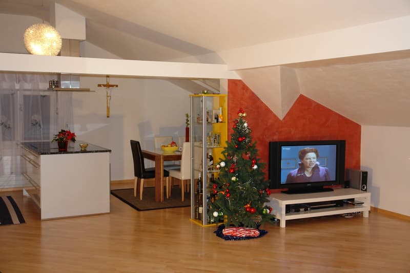 Living room with wooden floor, dining table, chairs, Christmas tree, TV, cabinet, and kitchen island