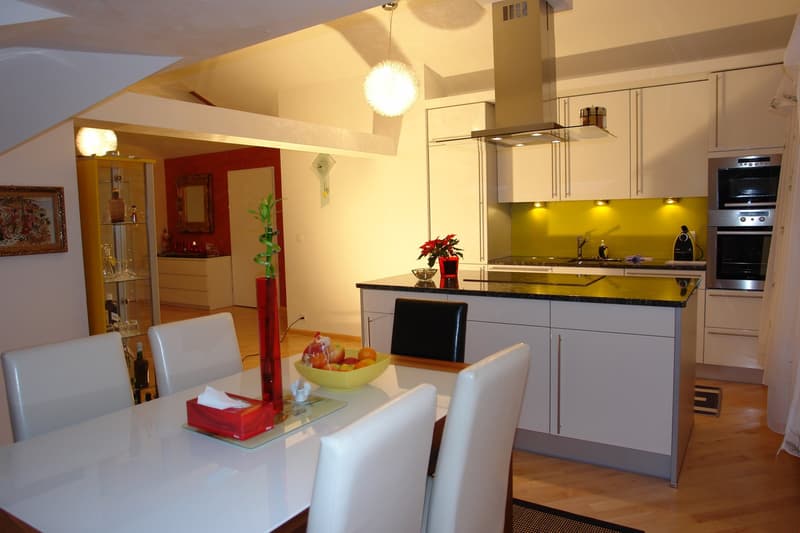 Dining area with a table, chairs, and a kitchen with a countertop, cabinets, and appliances.