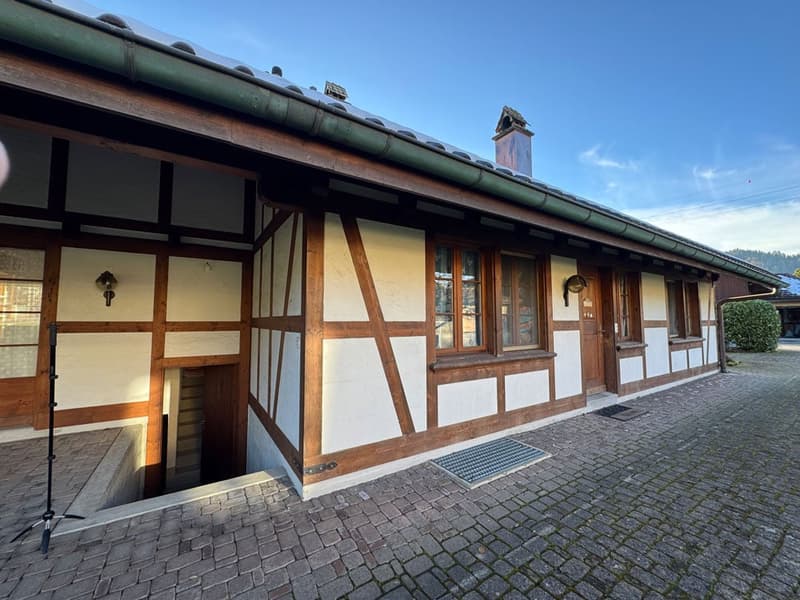 Traditional house, wooden beams, white and brown walls, brick pavement, entrance with steps, chimney, windows with wooden frames