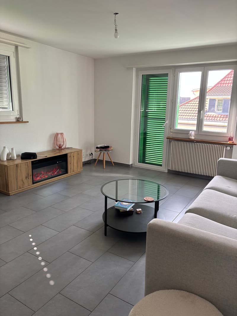 tiled floor, electric fireplace, large window, couch, coffee table, heater