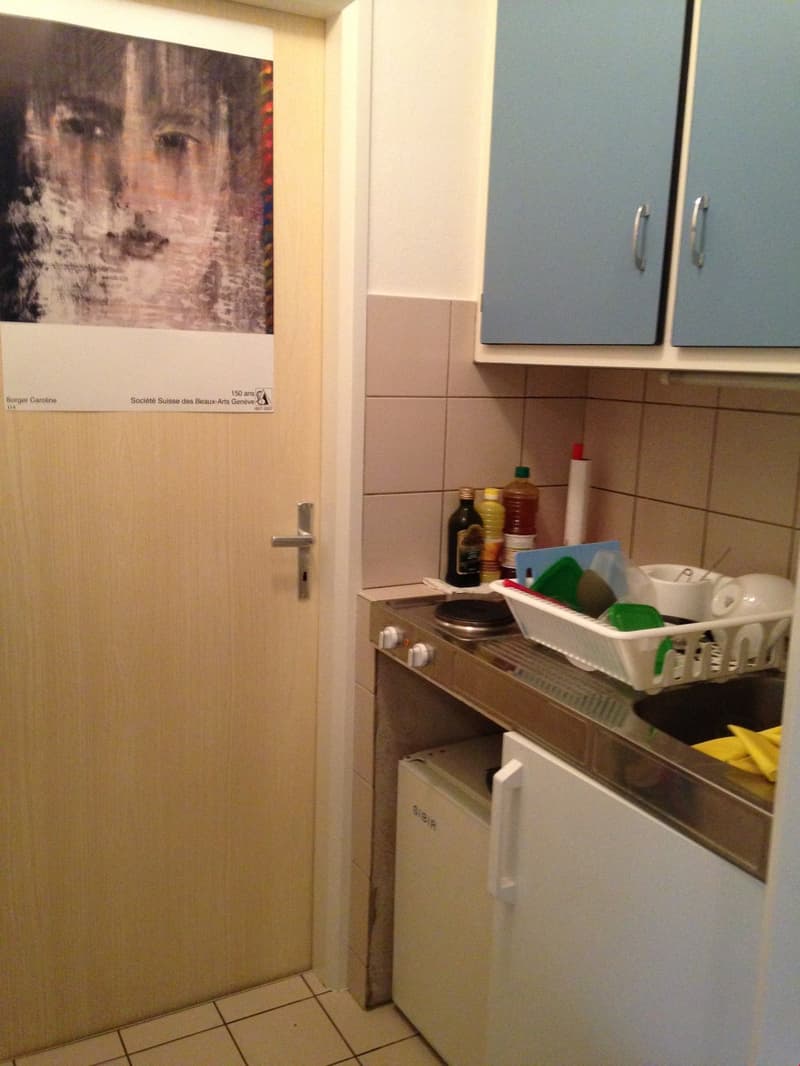 small kitchen with sink, stove, refrigerator, cabinets, and a door