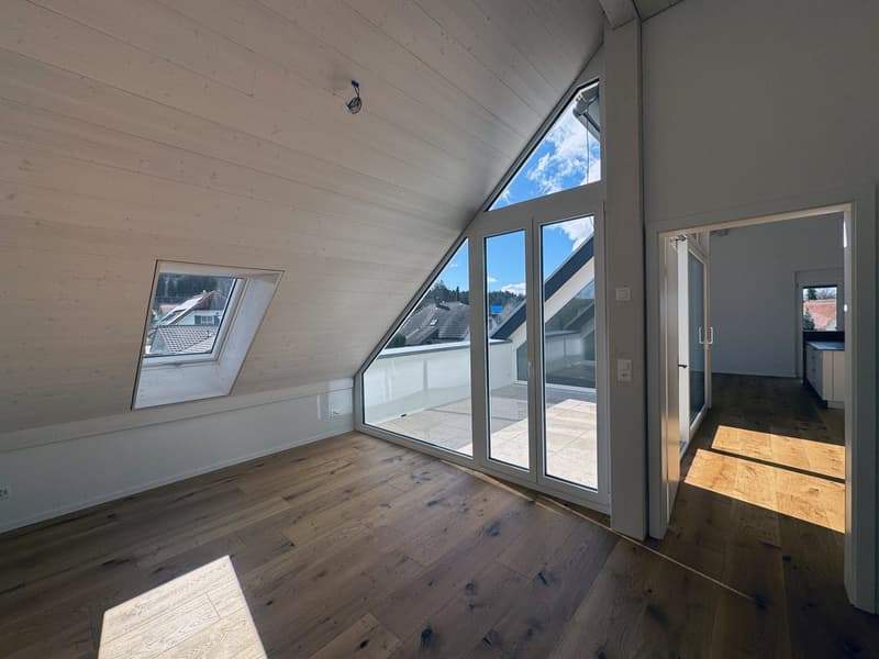angled room with sliding doors and large windows, hardwood floors, two smaller windows, light fixtures, slanted wooden ceiling