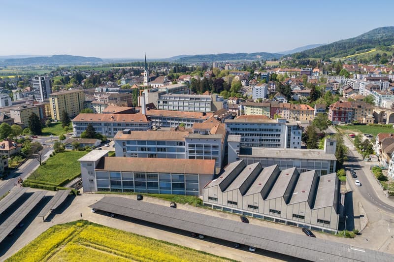 School building, multiple floors, multiple buildings, large parking lot, solar panels