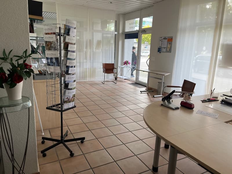 large entrance with chairs, tables, bulletin board, plants, large windows