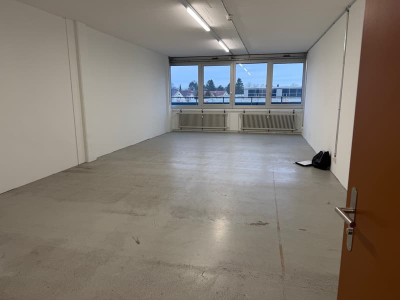 Empty room with white walls and ceiling, concrete floor, radiators, large windows