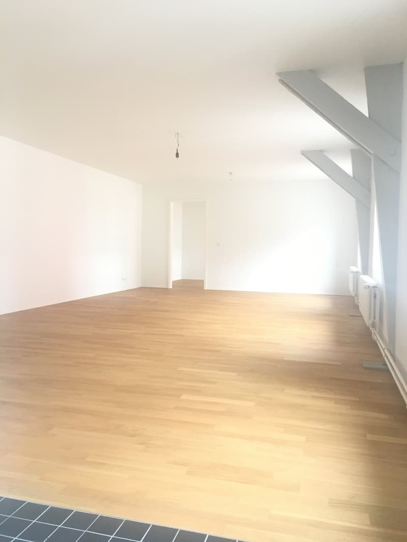 empty room, wooden floor, white walls, sloped ceiling, ceiling beam, doors