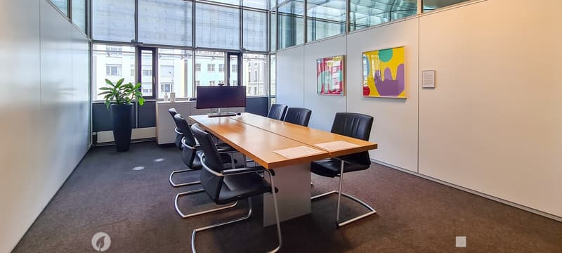modern conference room, long wooden table, black chairs, monitor, potted plant, glass walls, paintings