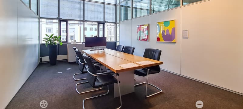 modern conference room, long wooden table, black chairs, monitor, potted plant, glass walls, paintings
