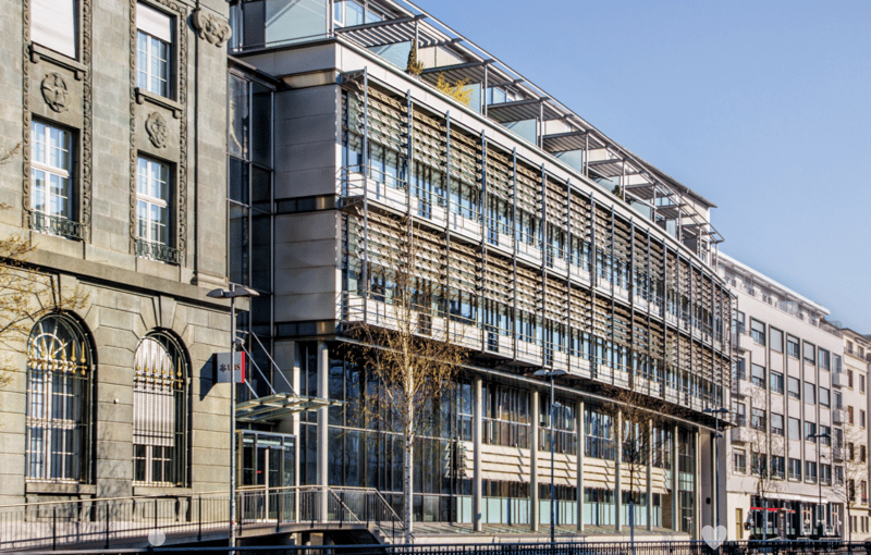 Gray building, large windows, metal railings, balcony, glass entrance, street lamp