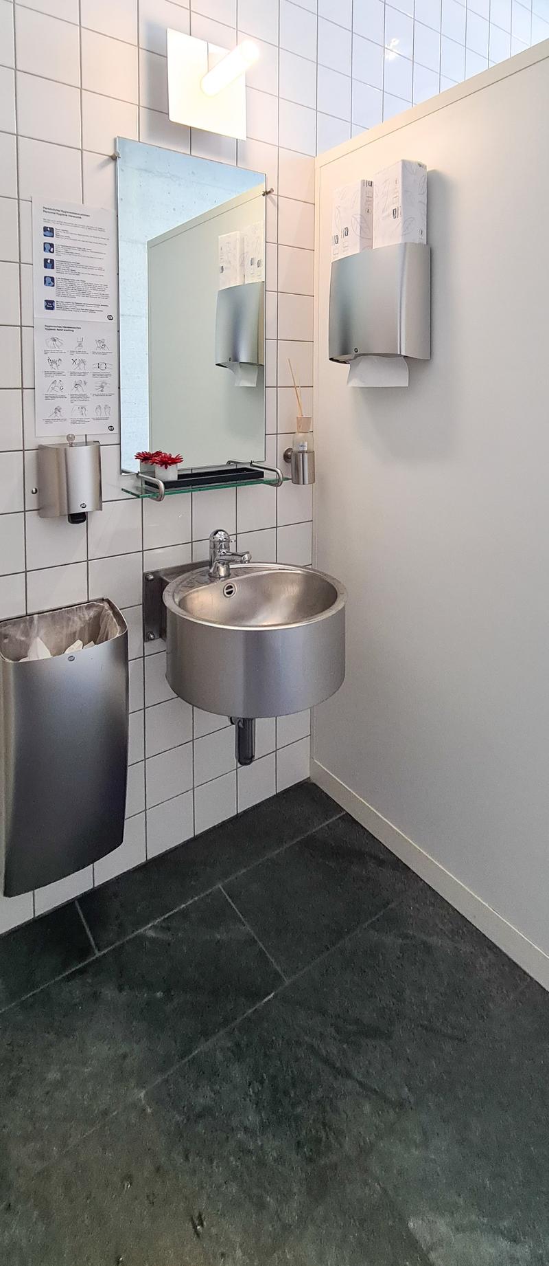 stainless steel sink, silver mirrors, tissue paper dispenser, trash bin