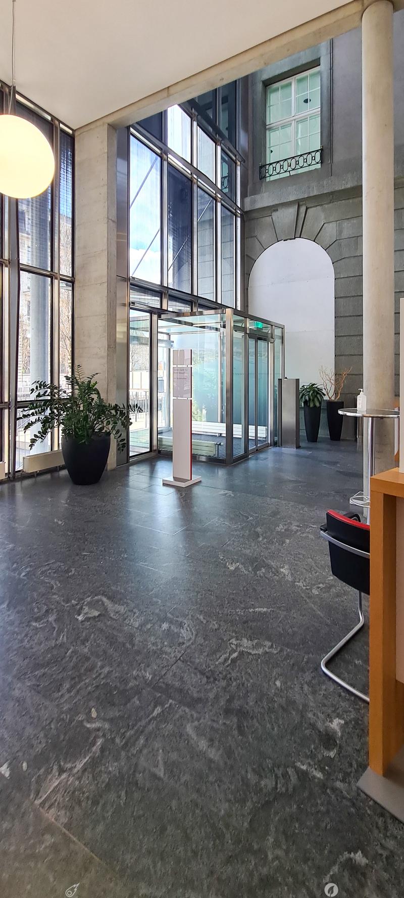 large lobby, marble flooring, large windows, plants, round table, lamp