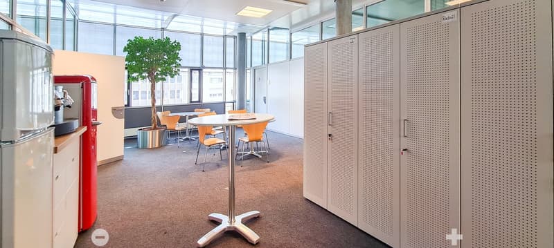a large office space with a round table, chairs, and potted plant