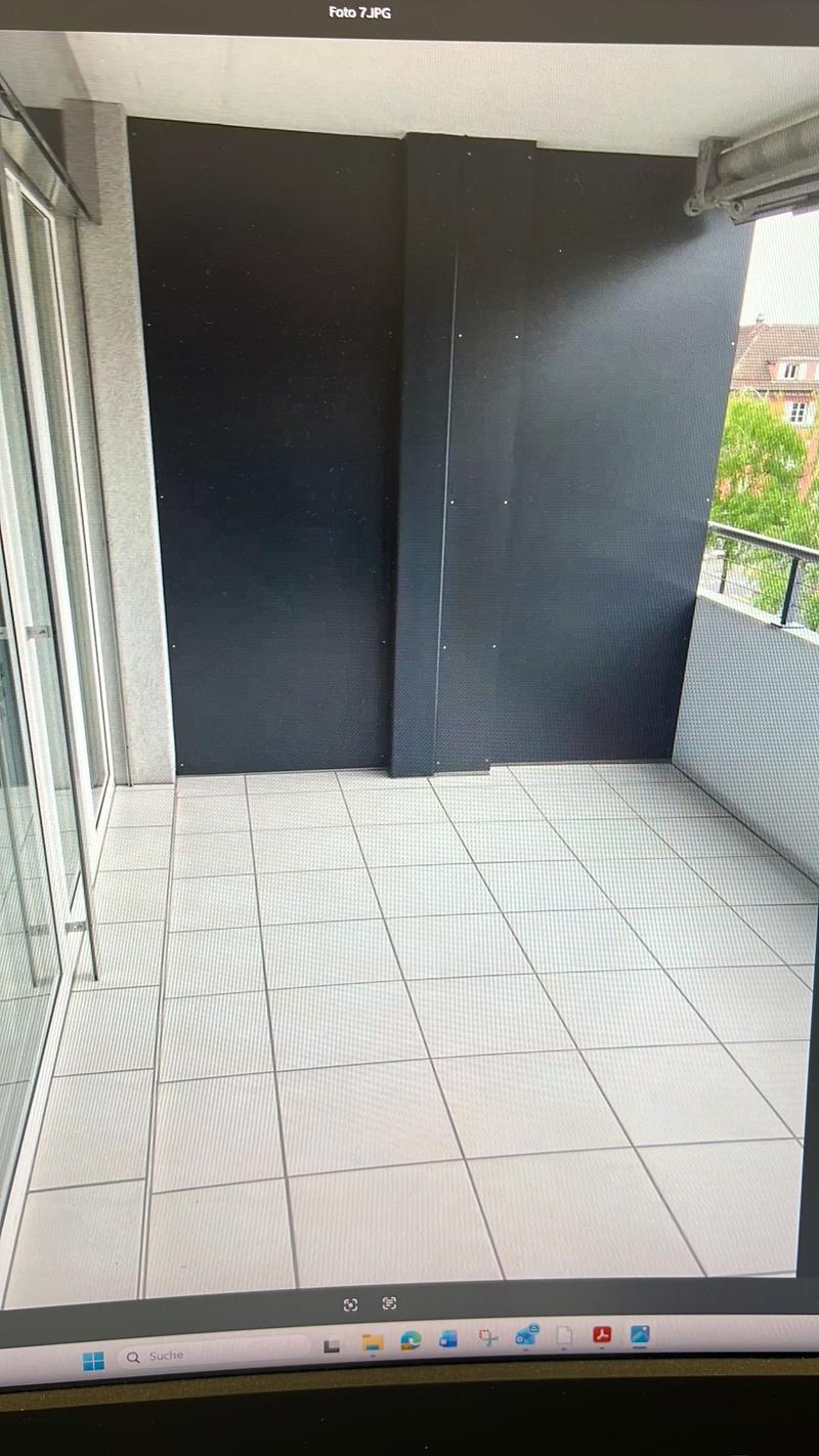 Empty balcony with white tiles, glass doors, black walls, metal railings