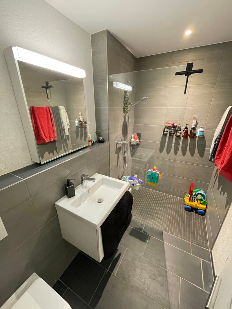 Bathroom with white sink, mirror, shower, and tiled floor