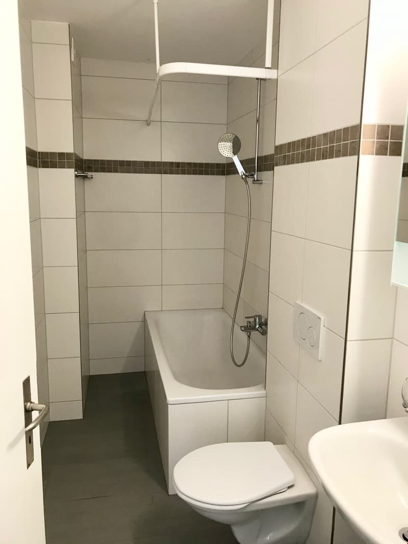 Bathroom with bathtub, toilet, sink, shower, white tiles, white walls, white floor