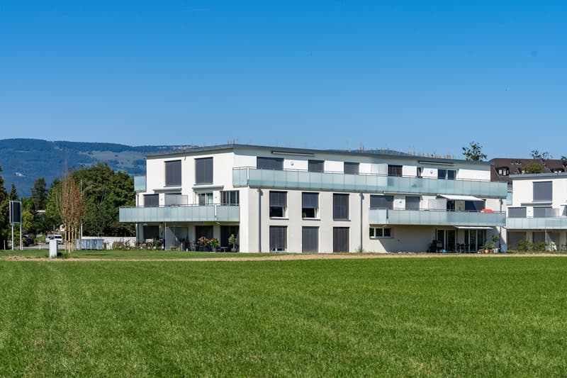 modern white building, balconies, garden, wide field in front