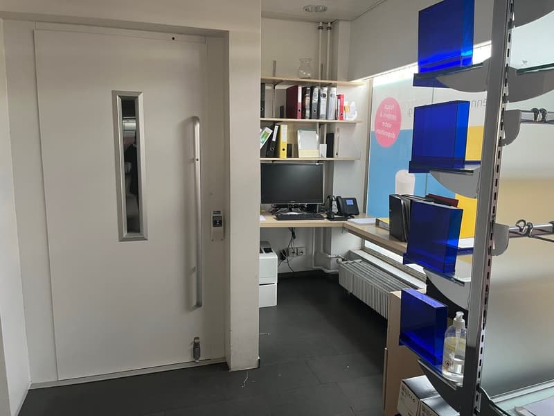 small office room with desk, computer, telephone, shelves, radiator, printer, door