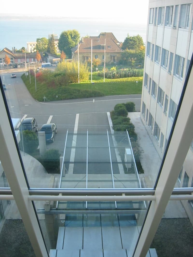 View from office building window showing a parking lot, cars, buildings, and distant sea