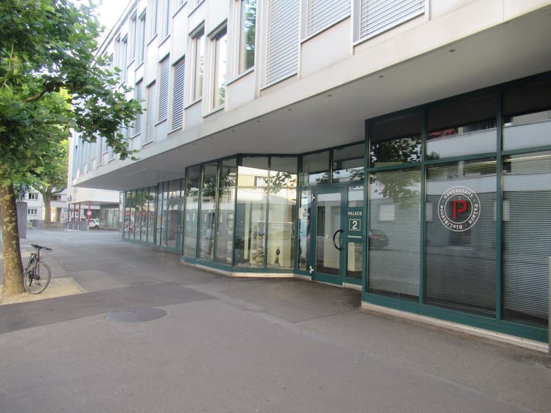 Modern building with glass facade, entrance with logo and number, glass doors, bicycle parked