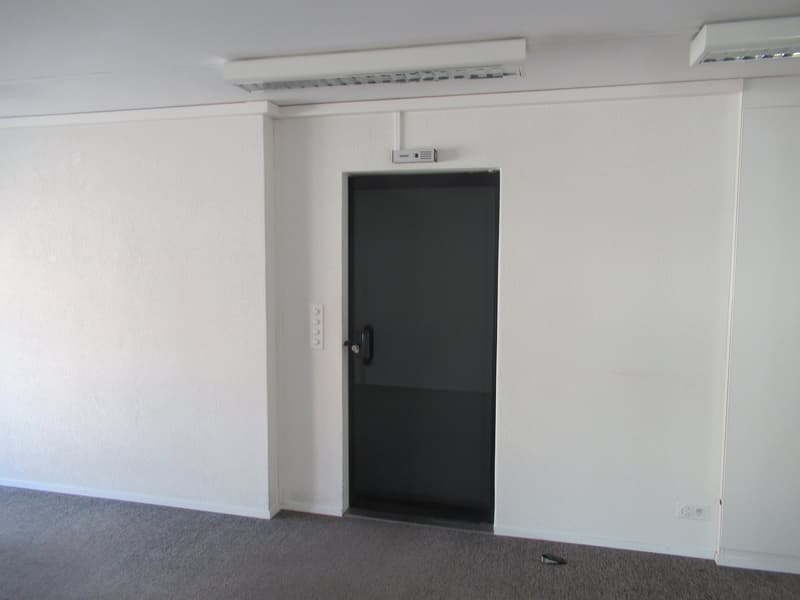 empty room with a door, white walls, gray floor, closed door