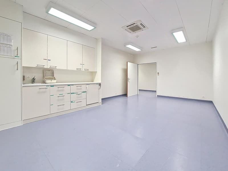 Empty room with white walls, white cabinets, and gray floor.