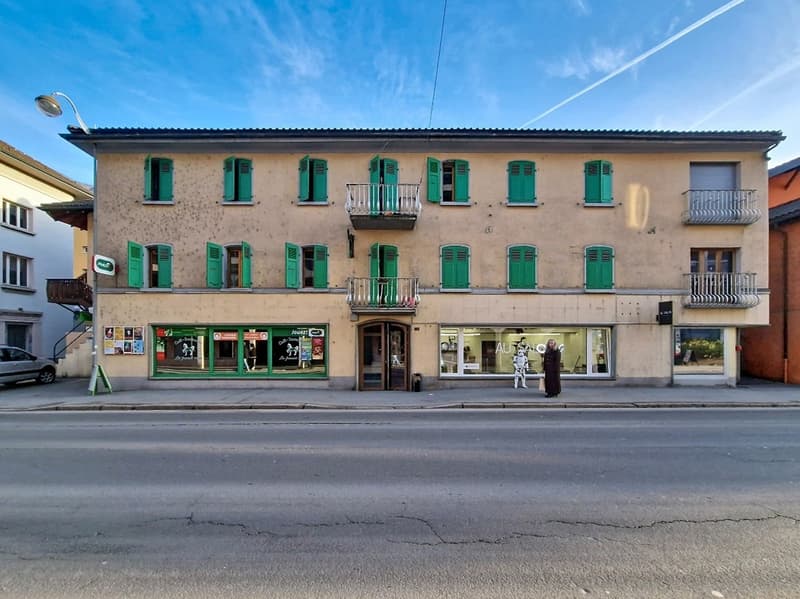 3 story building, green shutters, balconies, storefronts, street lamp