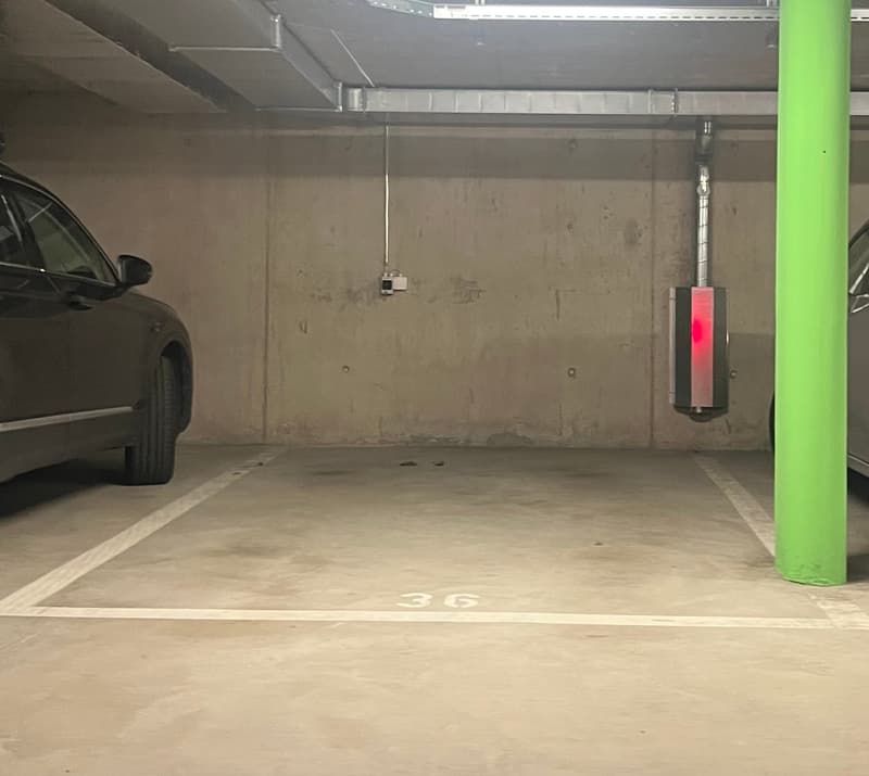 concrete parking space with two cars parked, parking space number 36