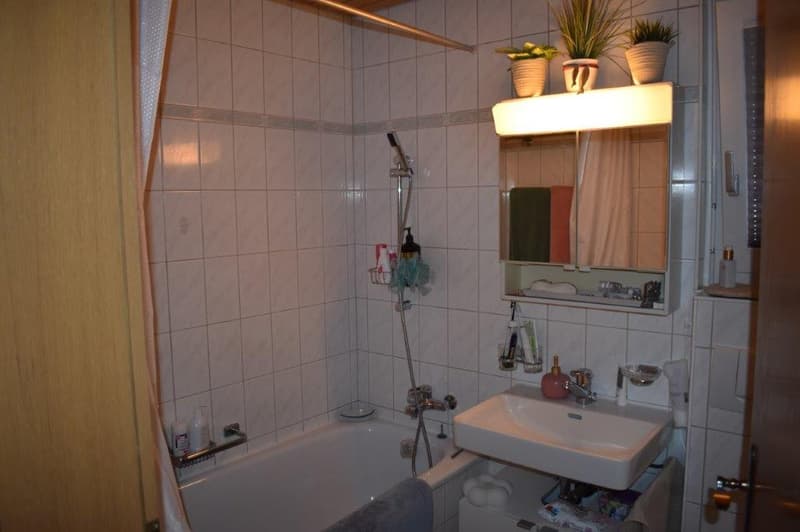 Bathtub, sink, shower, toilet, shelves, curtain, light, towels, bottles, hand soap