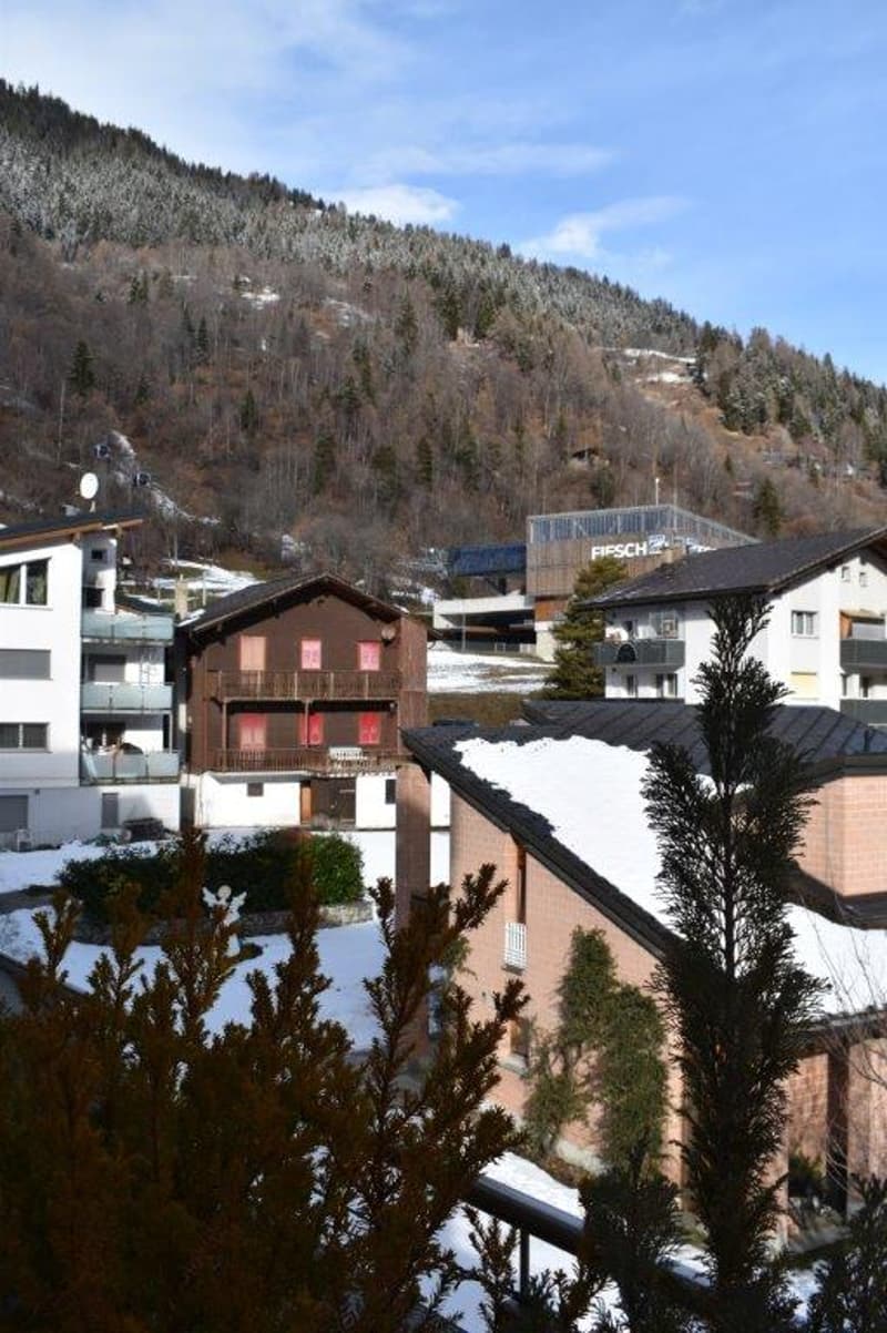 building complex with several houses, surrounded by mountains and snowy hills