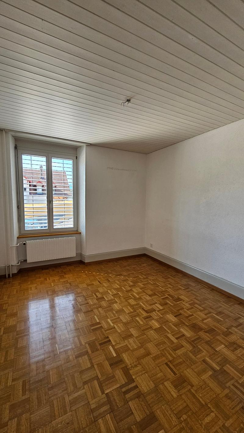 Hardwood parquet flooring, white walls, windows with white shutters, central heating radiator