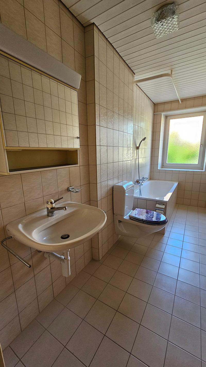 Bathroom with white tiles, bathtub, toilet, sink, window