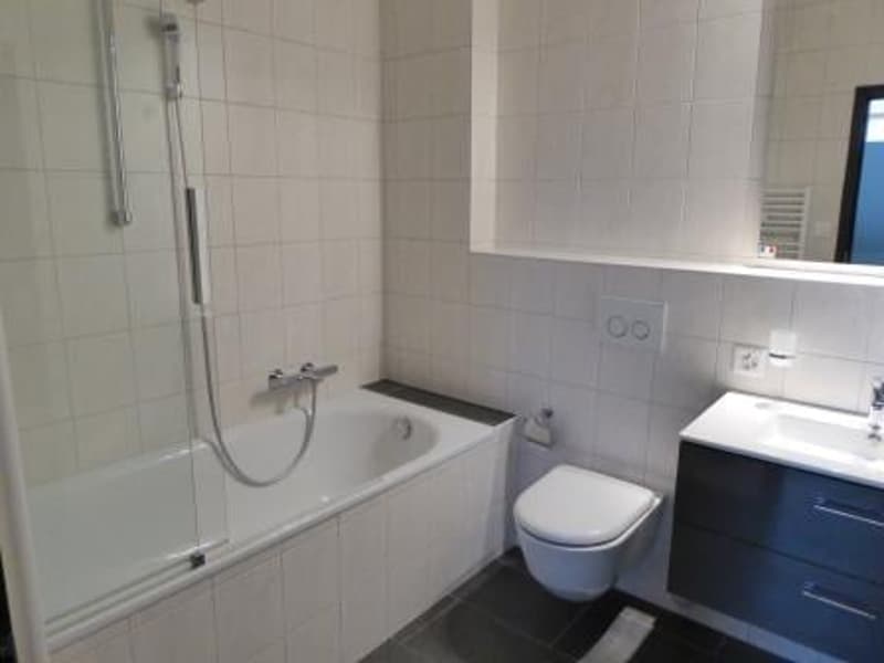 The image shows a bathroom with a bathtub, shower, toilet, and a vanity with a sink.