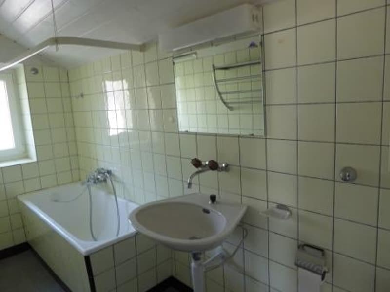 Tiled walls, bathtub, sink, and mirror in a simple, functional bathroom layout.