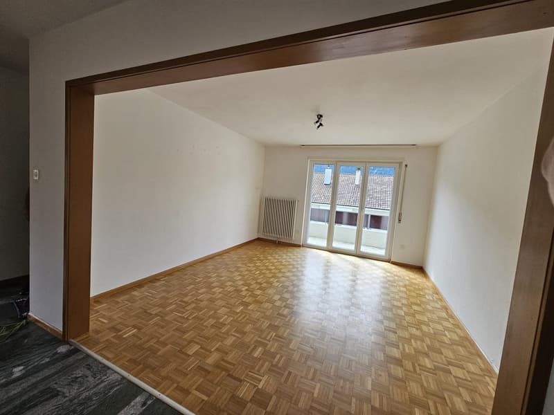 empty room, wooden parquet floor, sliding doors to balcony, white walls, radiator