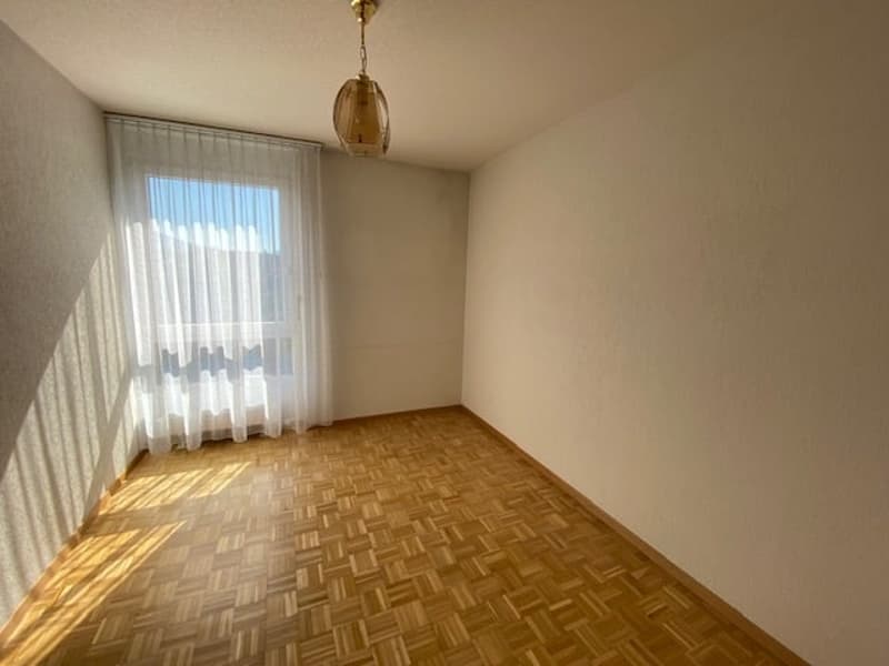 Empty room, white walls, wooden parquet flooring, white curtains, ceiling lamp