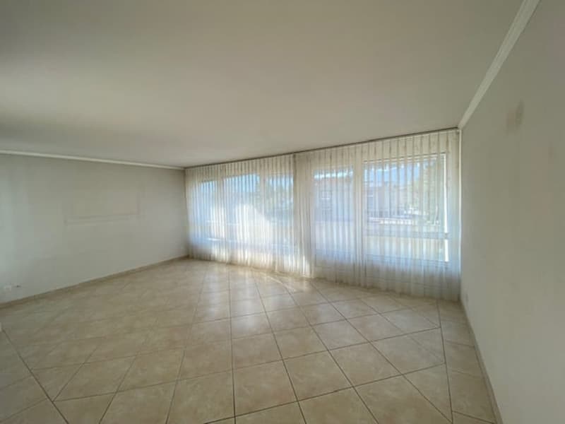 empty room with beige tiles, white walls, white curtains, and windows
