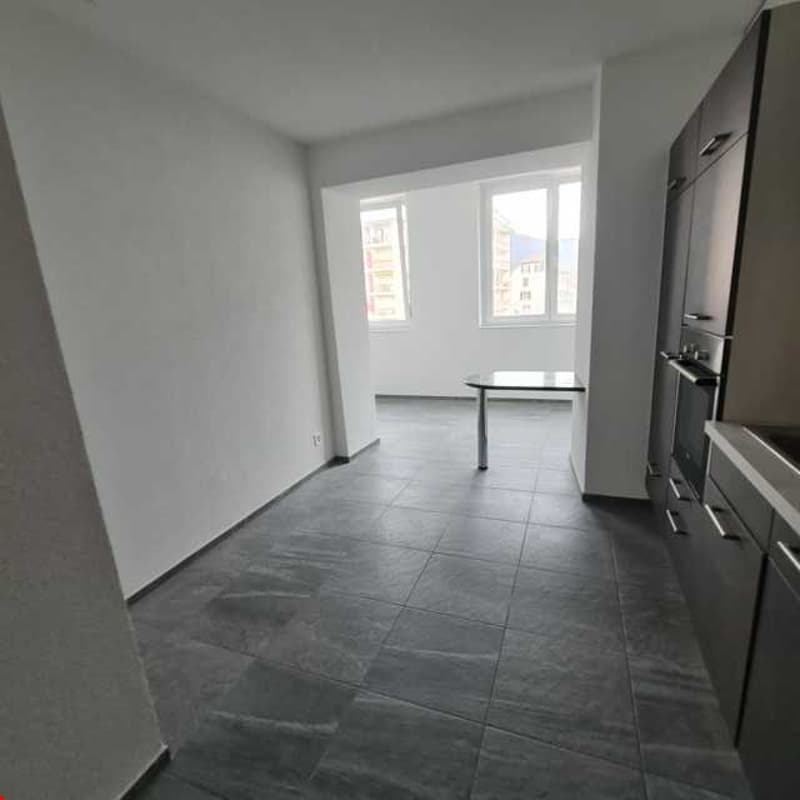 Kitchen: empty kitchen with dark flooring, kitchen cabinets, table, oven