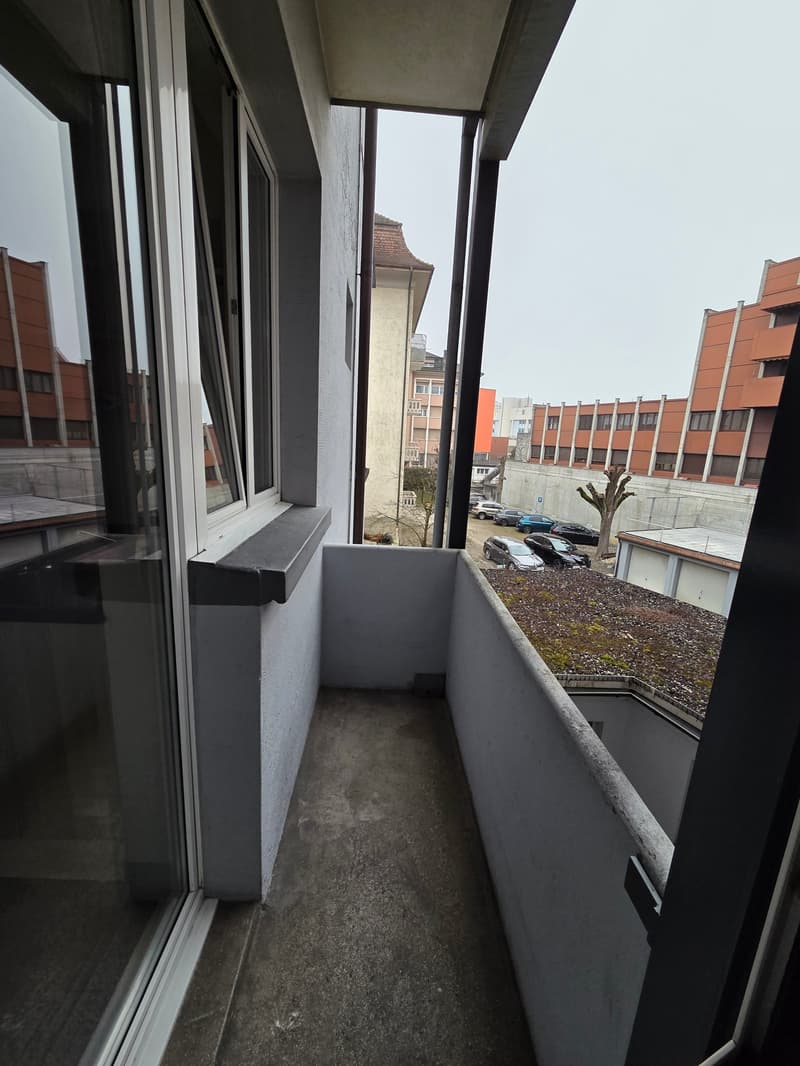 concrete balcony with a window, railing, and a black floor
