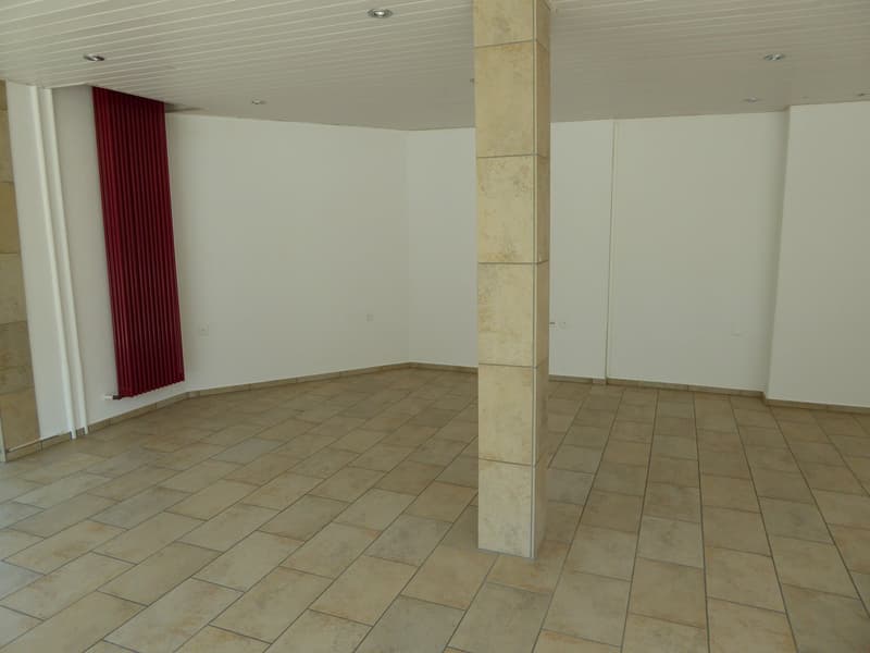 Large empty room, tiled floor, red curtain, pillar, two doors